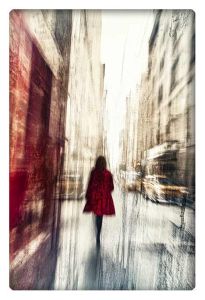 Blurred silhouette of a woman in a red coat walking through the streets of a bustling city.